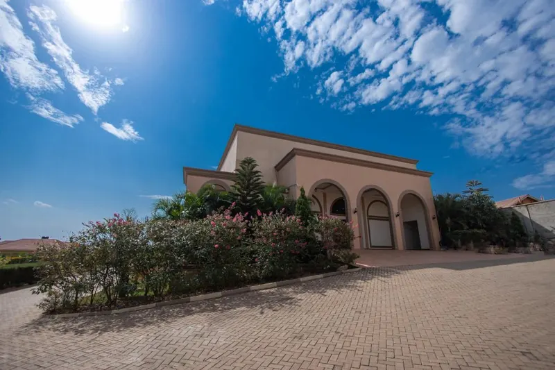 The A&M head office at Nsambya Gardens, Kampala: an arched building beside a paved driveway