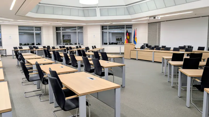 A formal assembly chamber with rows of desks and national flags